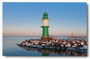 Ein grüner Leuchtturm an einem felsigen Ufer in der Serie Leuchttürme - Warnemünde.