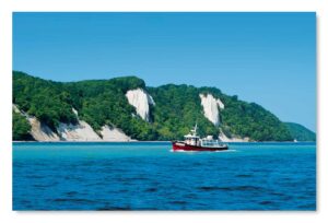 Ein Boot von Rügen - Meine Insel - Nationalpark Jasmund liegt im Wasser in der Nähe von Klippen im Nationalpark Jasmund.