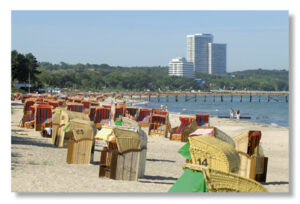 Im Küstenland - Timmendorfer Strand stehen Strandkörbe aufgereiht im Sand.