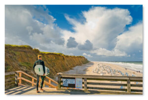 Sylt Impressionen: Eine Insel – ein Mann – ein Board auf einer Holzpromenade.