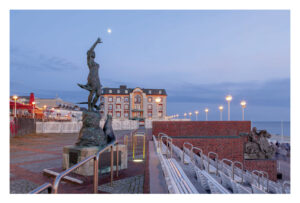 Eine Trauminsel - Westerland - Seepromenade-Statue auf einer Seepromenade in der Abenddämmerung.