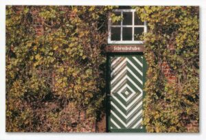 Eine Tür aus Efeu an einer Backsteinwand.